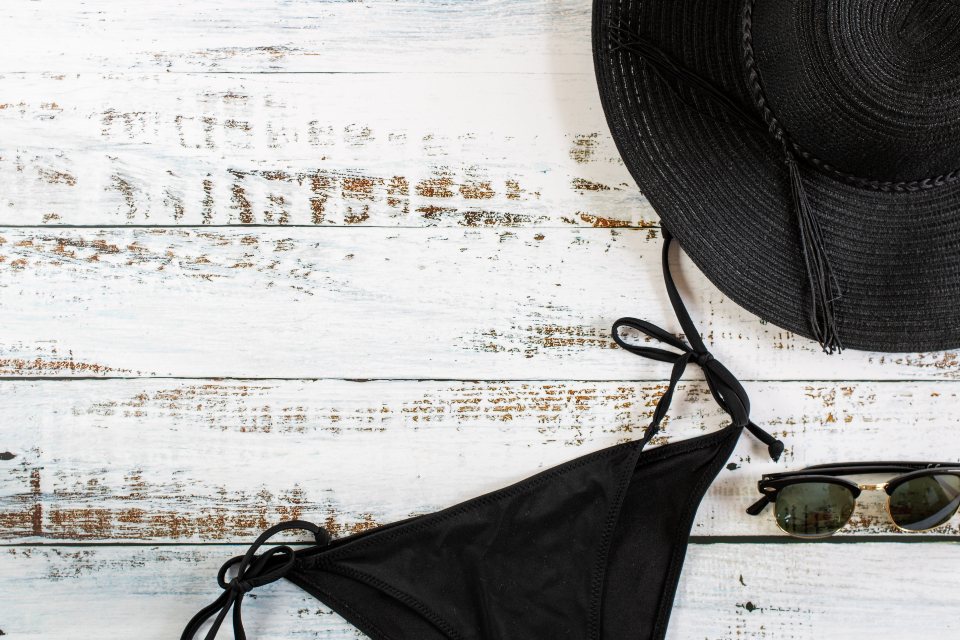 Accessoires de plage noirs posés sur le sable — été 2026, manucure résistante pour vacances You Rêve Paris