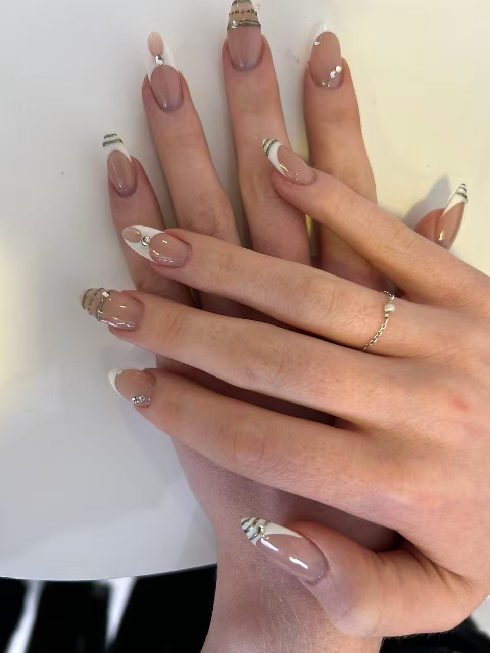 Ongles en amande nude, french blanche, fines lignes argentées et petits strass sur quelques doigts